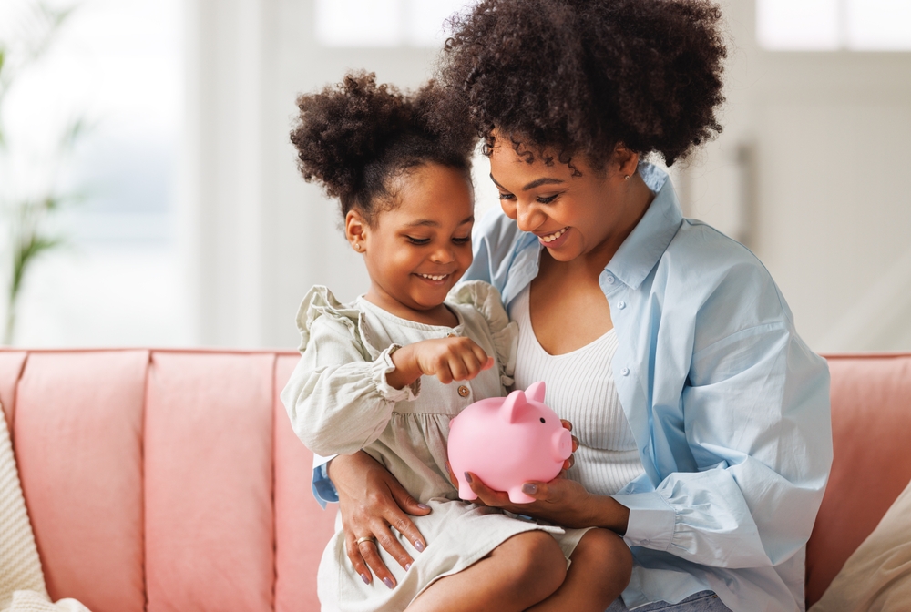 Mother and young child putting coins into a piggy bank.