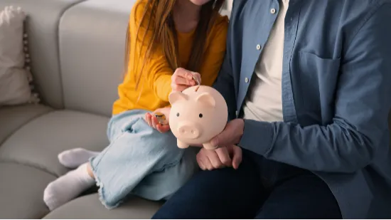 Adult holding piggy bank with child