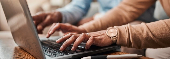 A couple typing on a laptop
