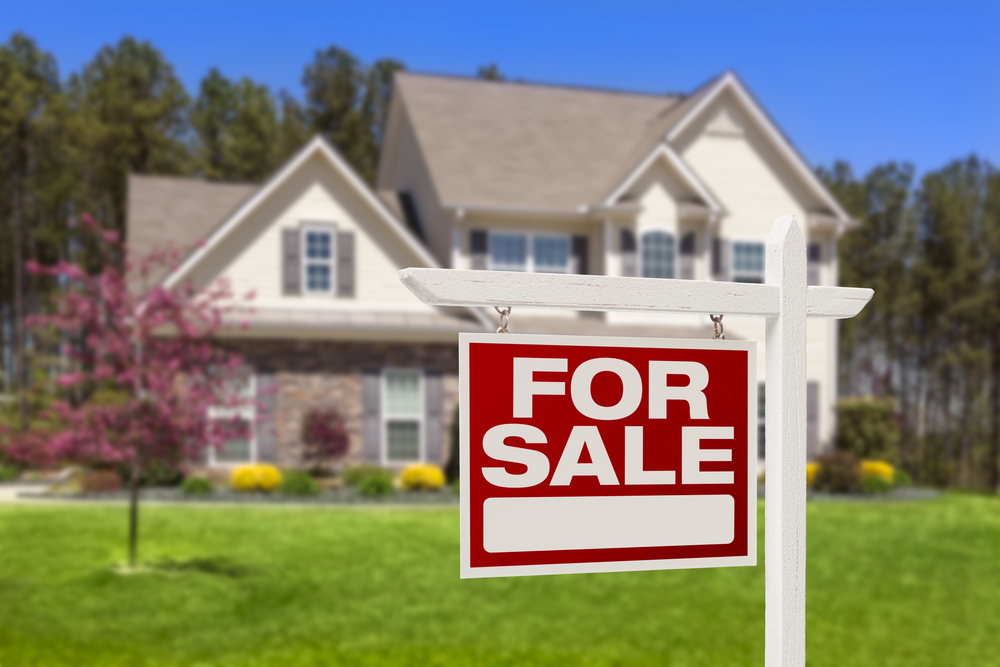 House with for sale sign in front.