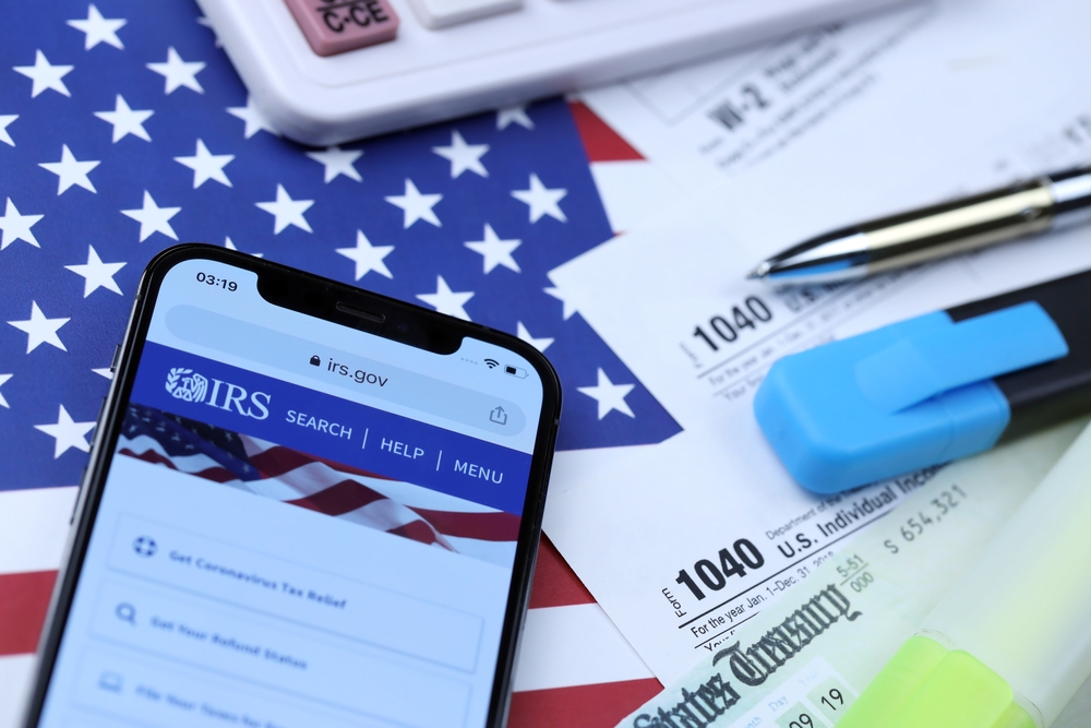 An image of tax papers and a phone displaying the IRS website