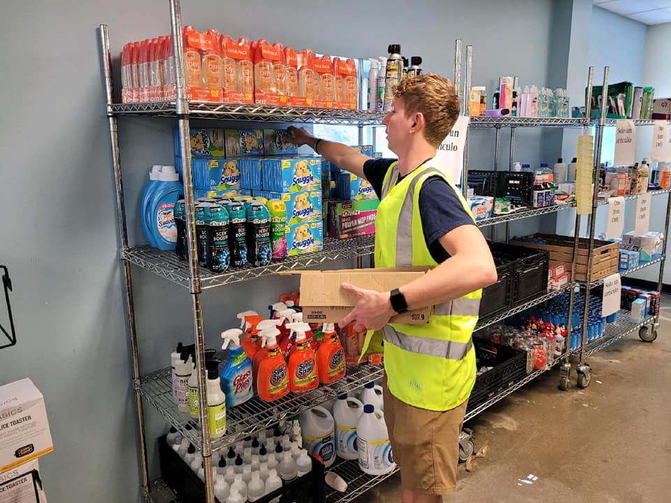 A volunteer stocking laundry essentials at Community Harvest Food Bank