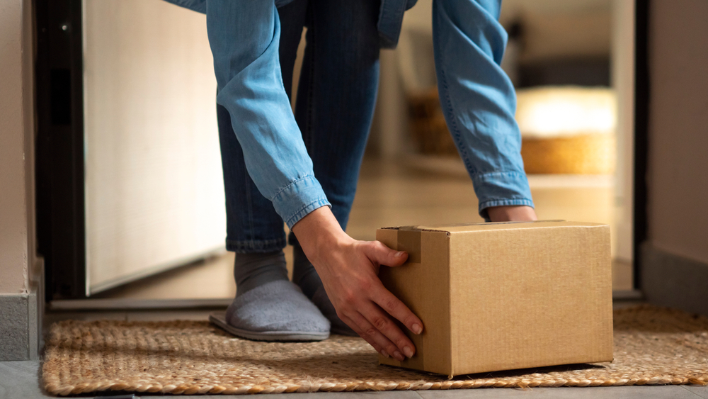 Image that depicts someone picking an unmarked package up from outside their door