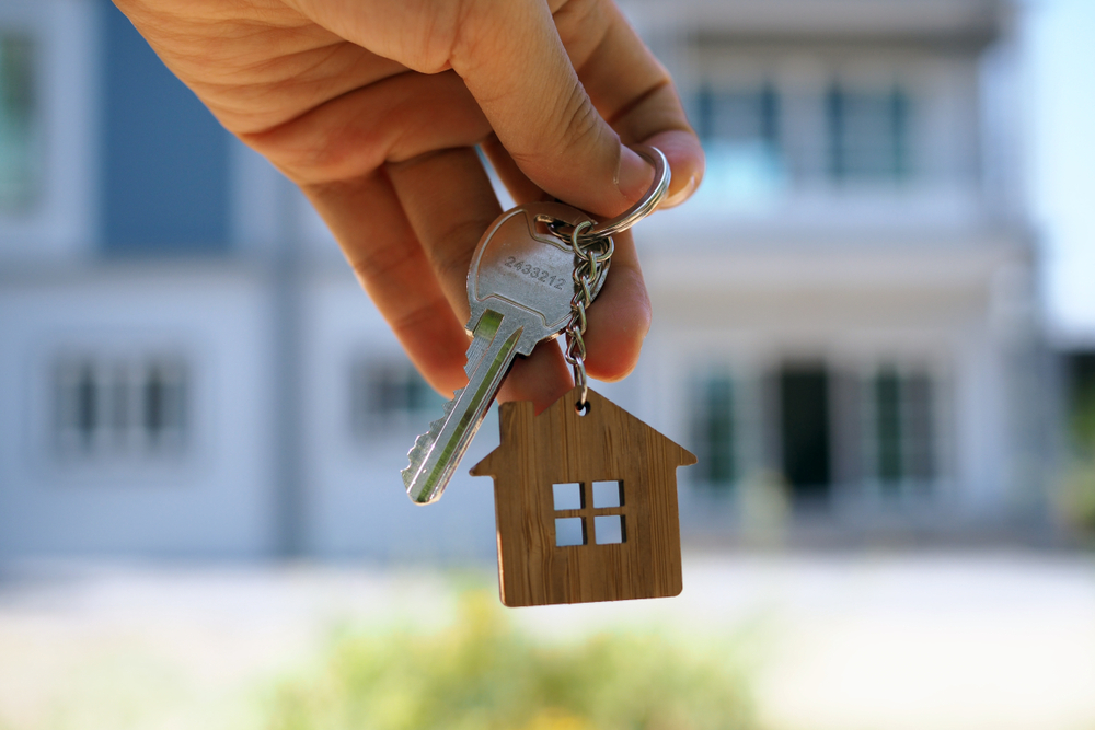 Holding a key in front of a house.