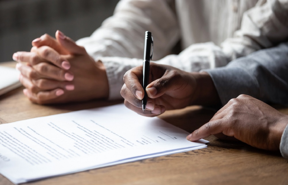 Hands signing a document.