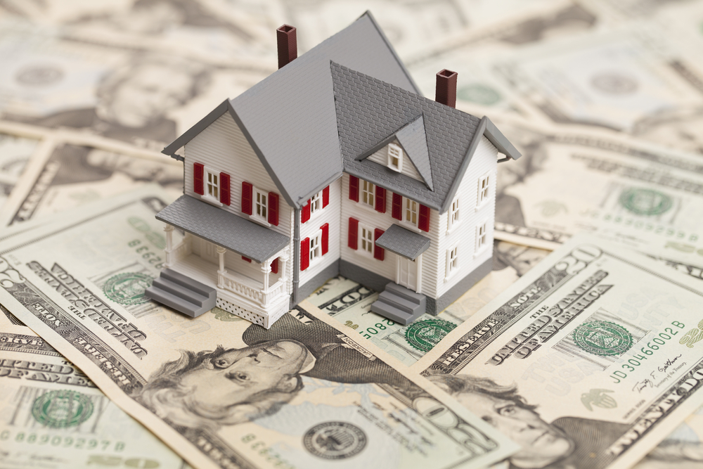 A small house sitting on top of US bills