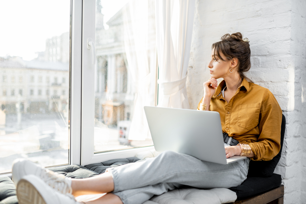Woman on laptop looking out window