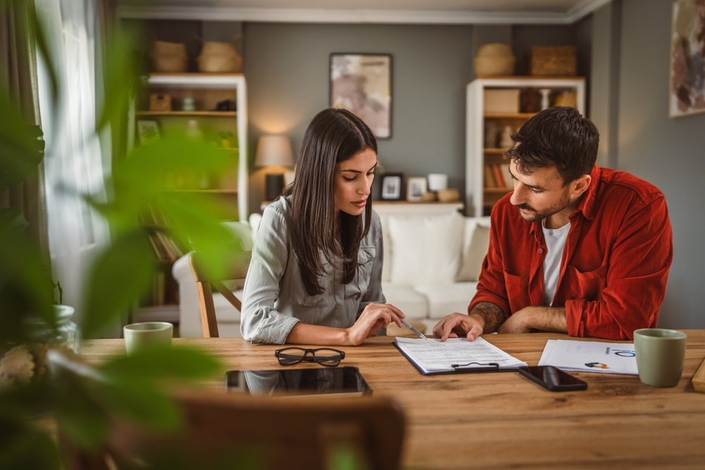 Couple reviewing financial documents at dining table