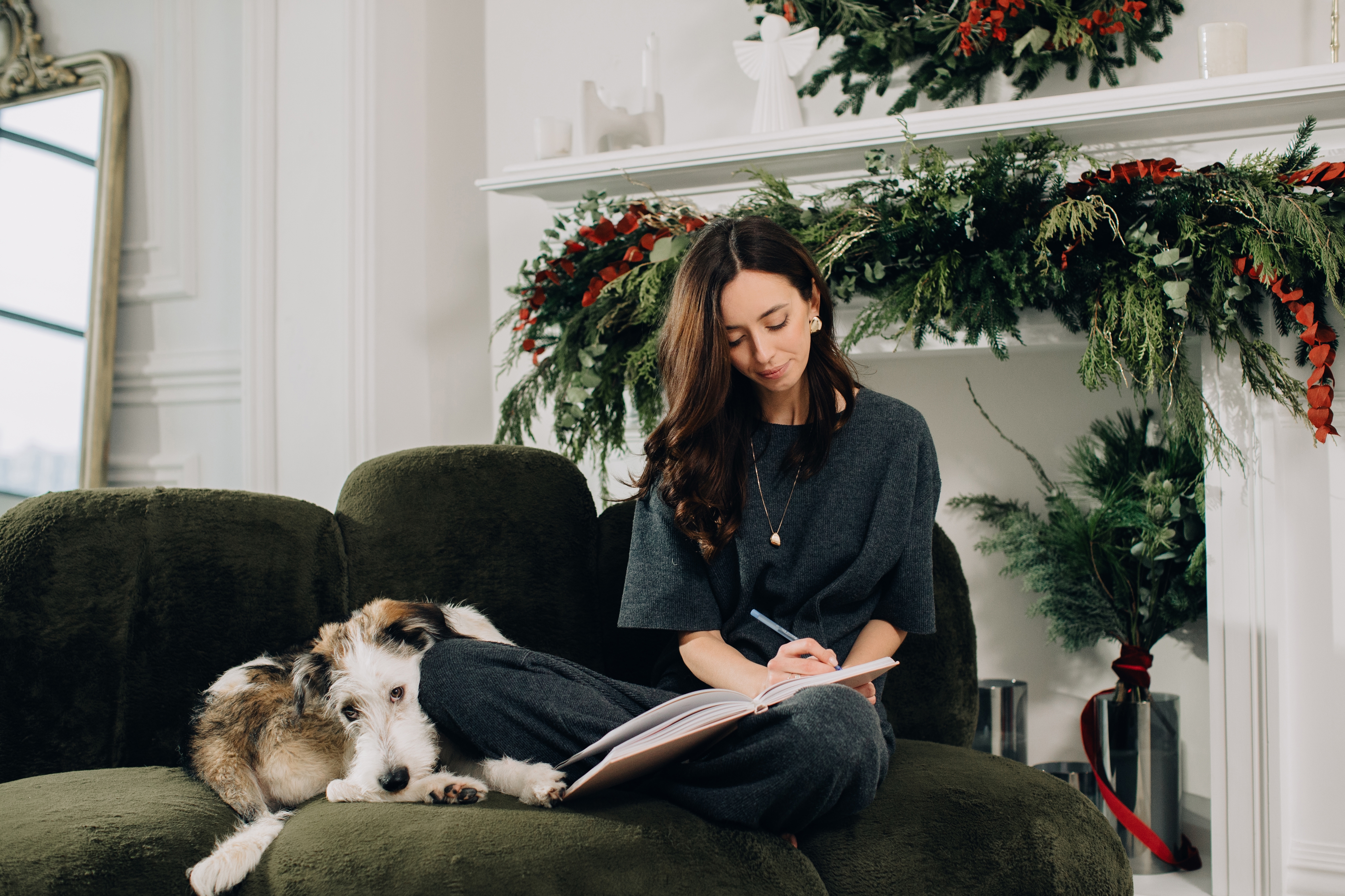 Woman sitting on sofa with dog while journaling