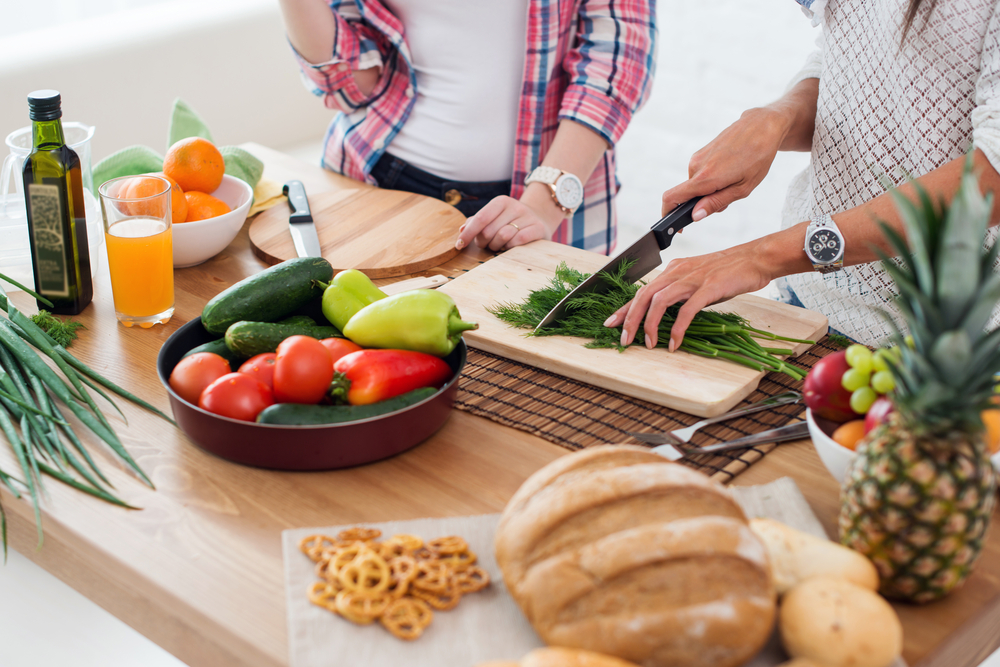 Close up of two people preparing a salad.