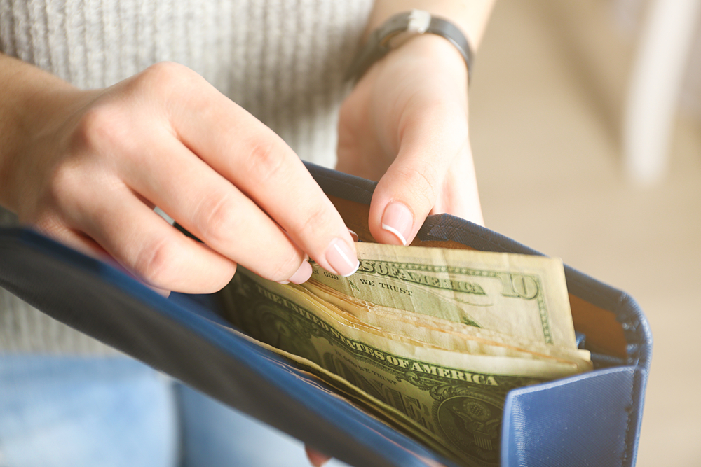 Close up of hands holding wallet full of cash.