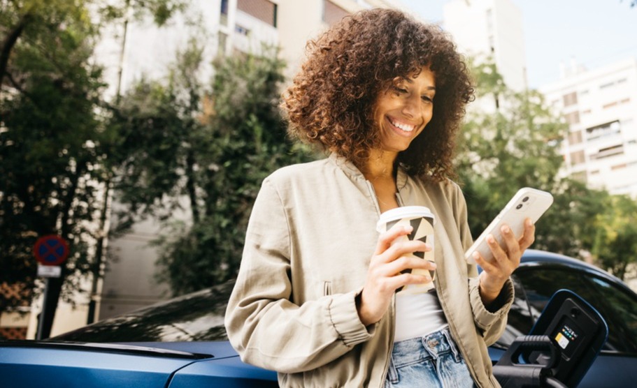 woman leaning on her car looking at her phone